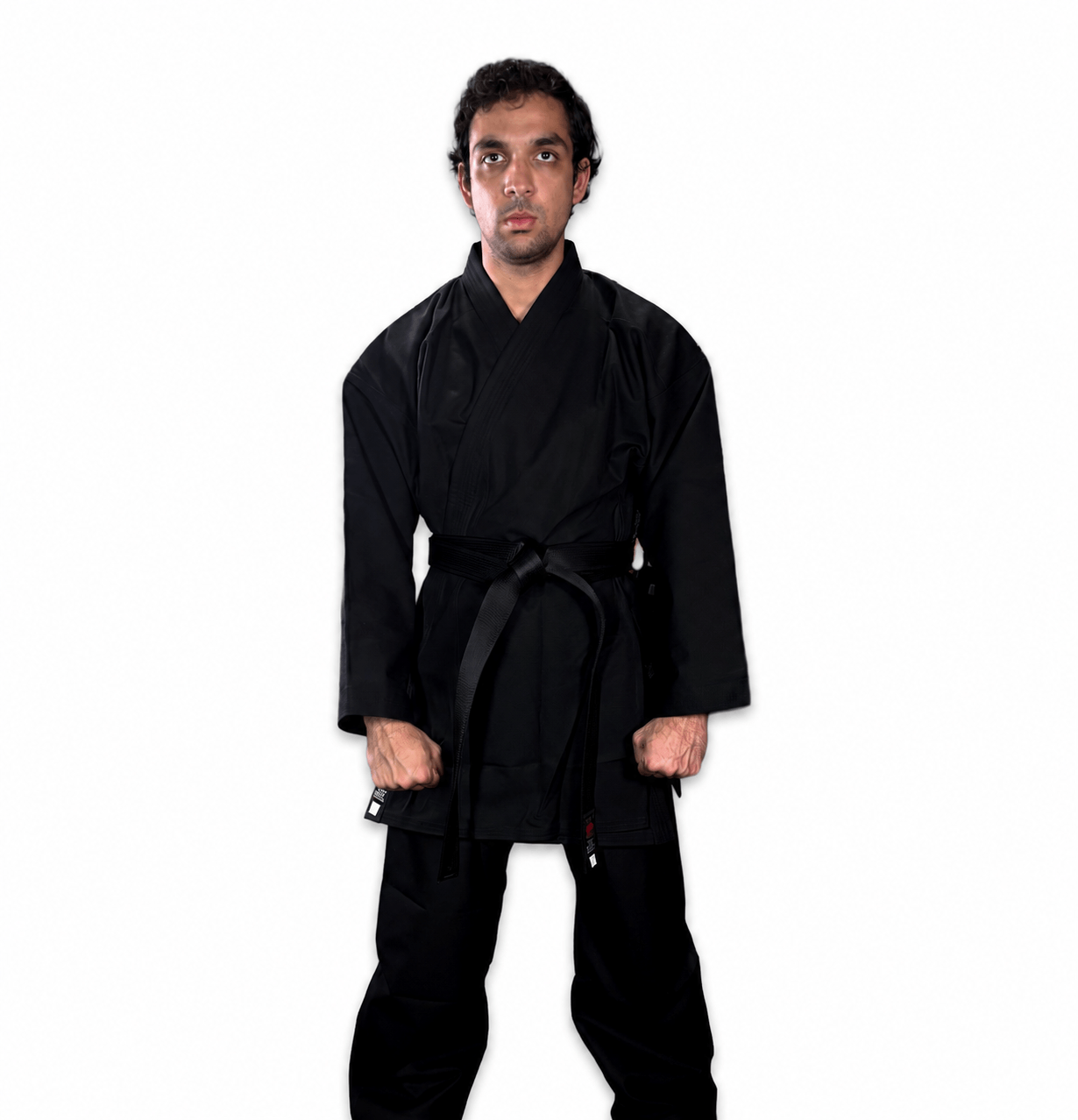 Karate practitioner in a black Shureido gi uniform executing a dynamic blocking and striking stance against a clean background.