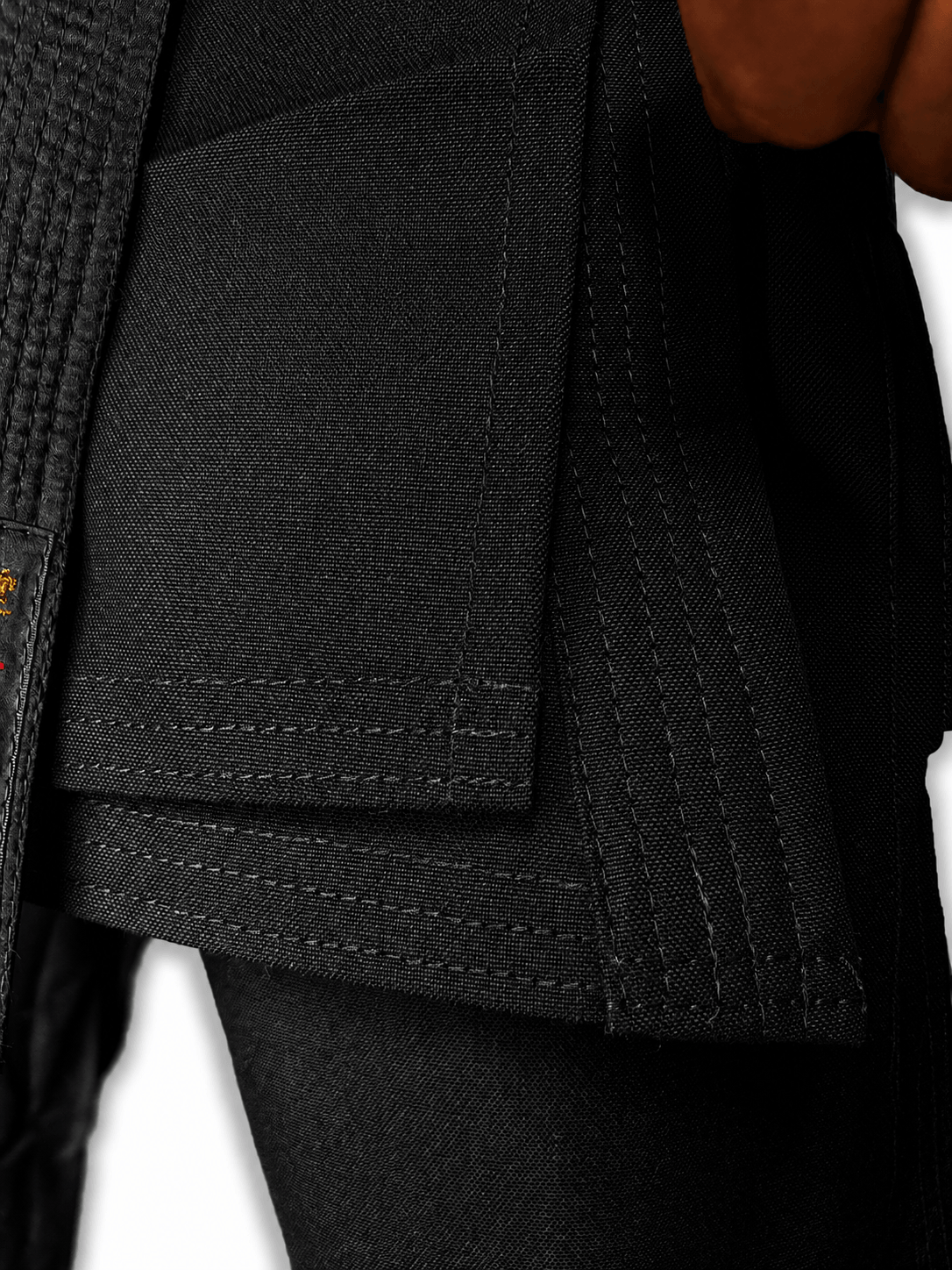 Close-up shot of the official red and gold Shureido brand label, size tag, and washing instructions stitched onto a black karate uniform jacket and black belt.