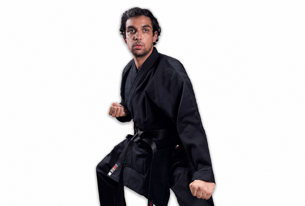 Martial artist wearing a premium black Shureido karate gi and black belt standing in a traditional ready posture against a white background.