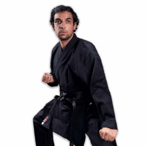 Martial artist wearing a premium black Shureido karate gi and black belt standing in a traditional ready posture against a white background.