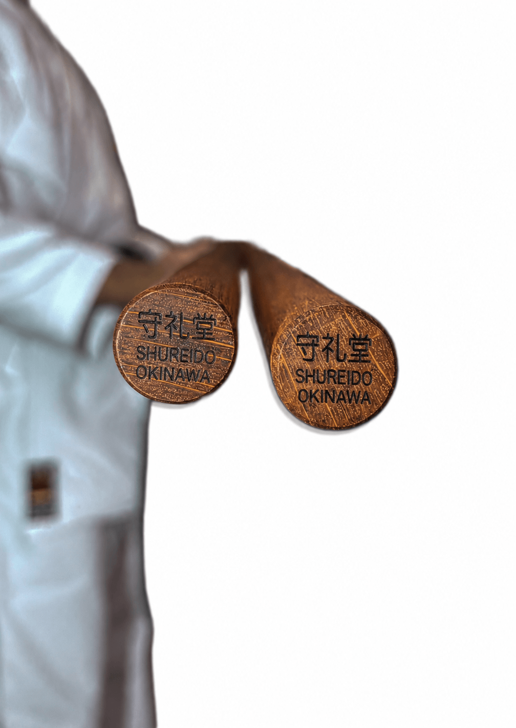 Close-up shot of a martial artist's hands gripping a traditional Shureido wooden bo staff against a white karate uniform and black belt.