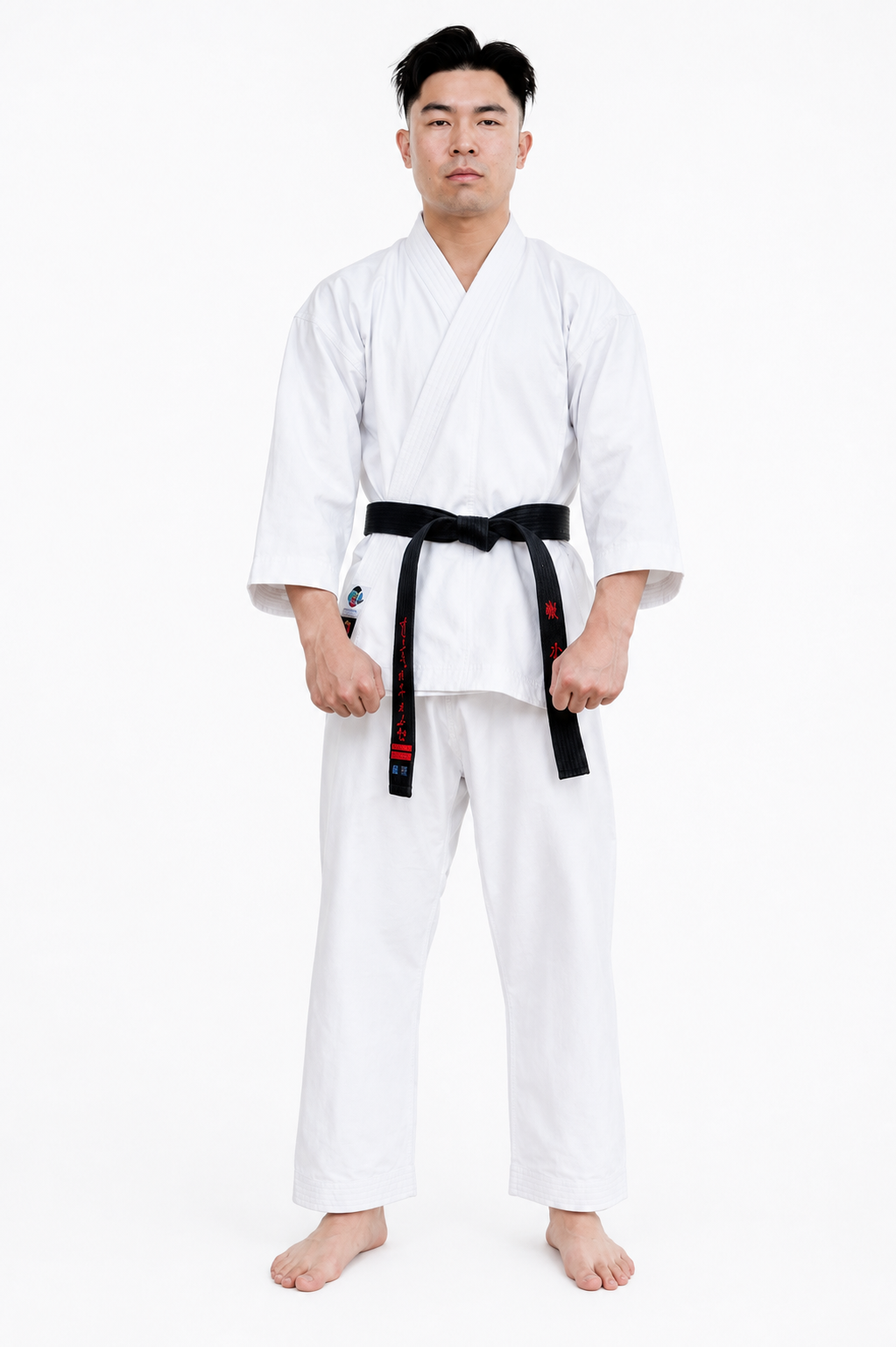 Male martial artist with a black belt standing in a natural stance, modeling the structured fit of the white Shureido Heavyweight K10 Gi
