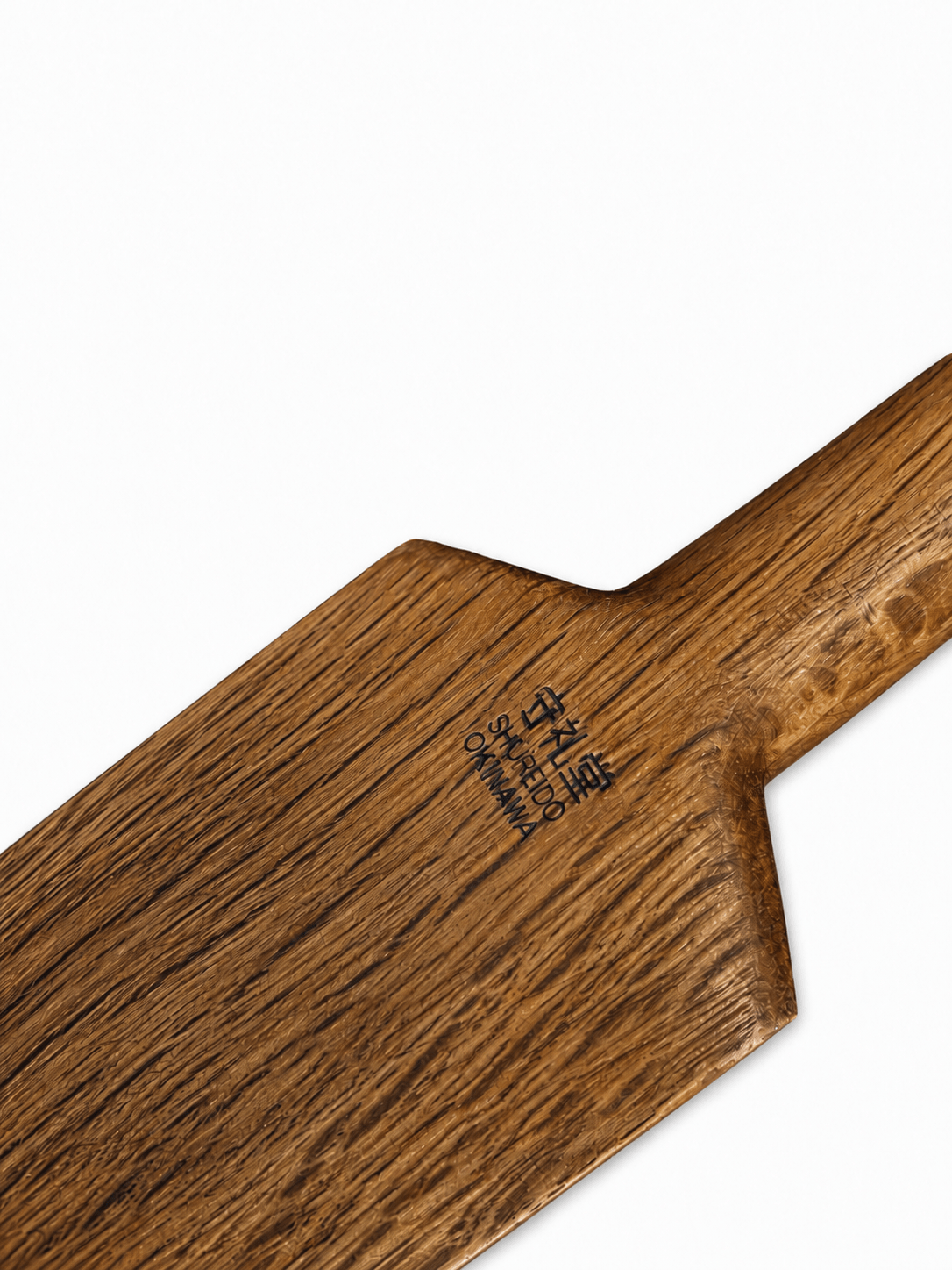 Close-up view of the engraved Shureido Okinawa brand logo and Japanese kanji text on the wooden blade of a traditional eku oar weapon.