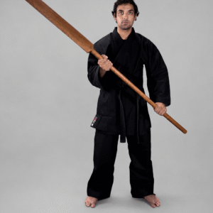 Martial artist wearing a black karate gi and black belt standing upright and holding a traditional Shureido Okinawan wooden eku oar weapon