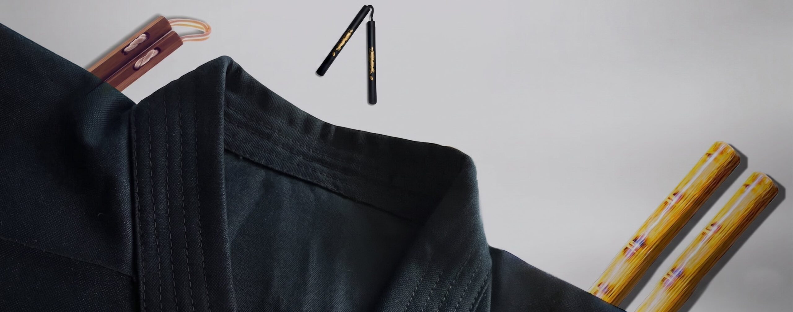 A folded black martial arts uniform top displayed alongside traditional wooden and black nunchaku against a light grey background.